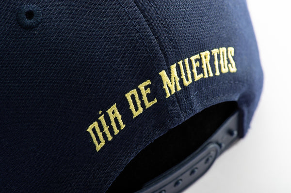 Club America Day of the Dead Snapback Hat with floral skull embroidered on the front, Club America embroidered on the side, "Dia de Muertos" embroidered on the back. The hat has a high crown, flat peak brim, and a snapback closure.